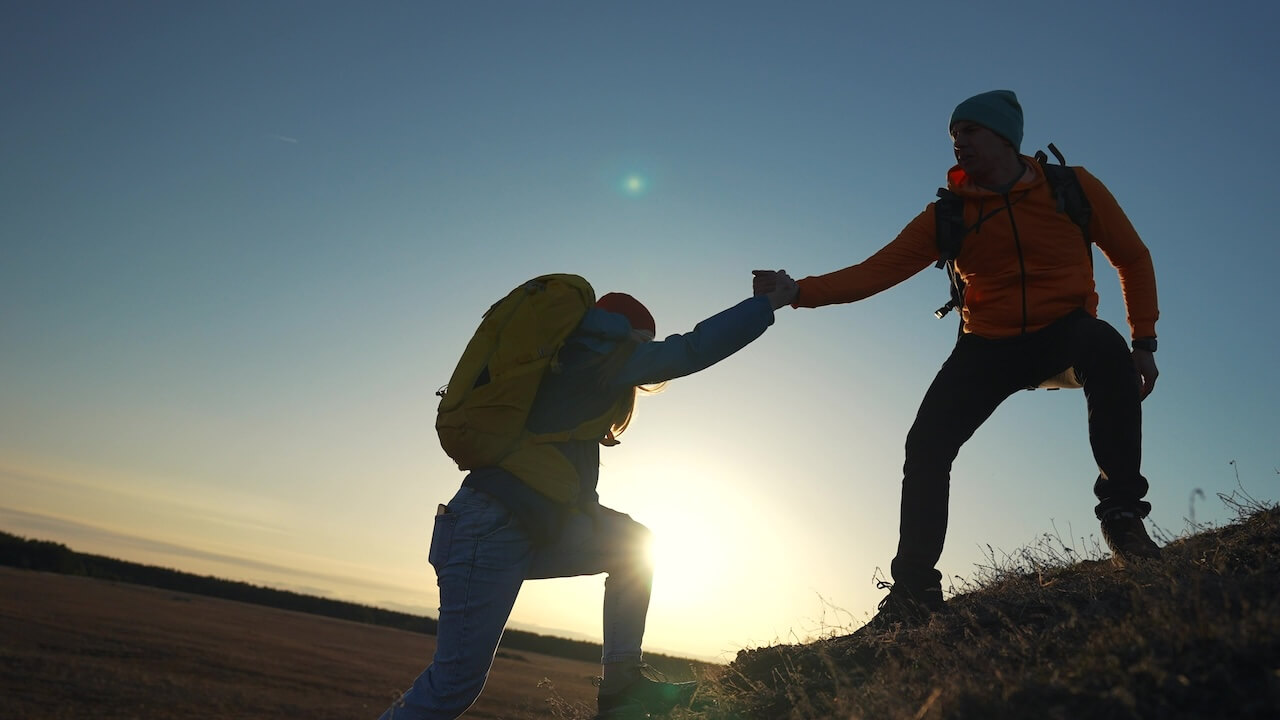 Two people on a hillside against a clear, twilight sky